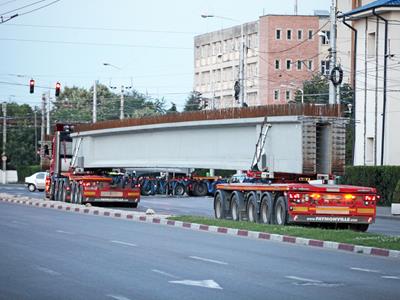 Das Fahrzeug wird zum Transport von Betonträgern eingesetzt. Kolossale Stücke, die 24 bis 46 Meter lang und zwischen 20 und 70 Tonnen schwer sind.