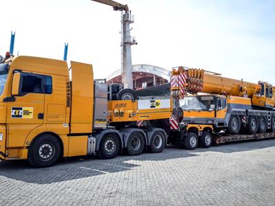 Hermosa combinación óptica de un camión semirremolque amarillo, una grúa móvil y un cargador bajo. El modelo Eurocompact de Scheuerle o el modelo THP de Goldhofer tienen características similares a las del vehículo modular CombiMAX. 